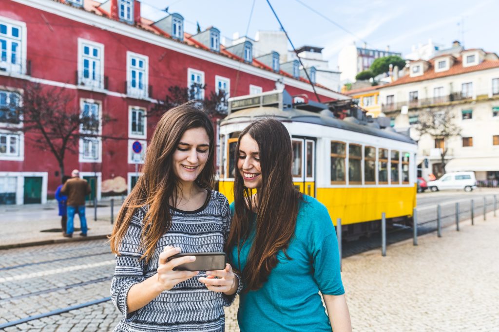 Girls with smartphone in Lisbon, tram on background