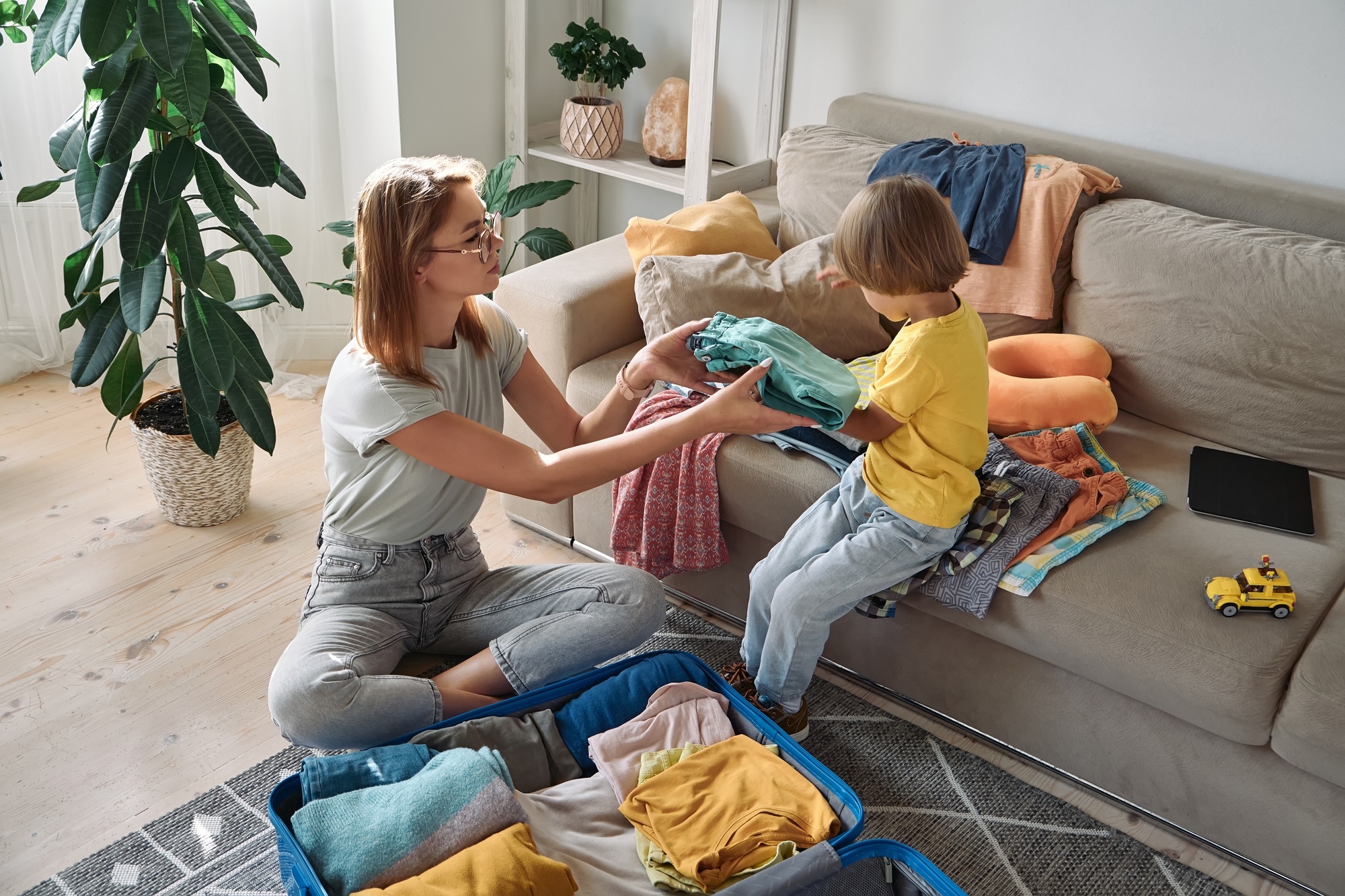 Mother and child are packing things in a suitcase together. Family relocation