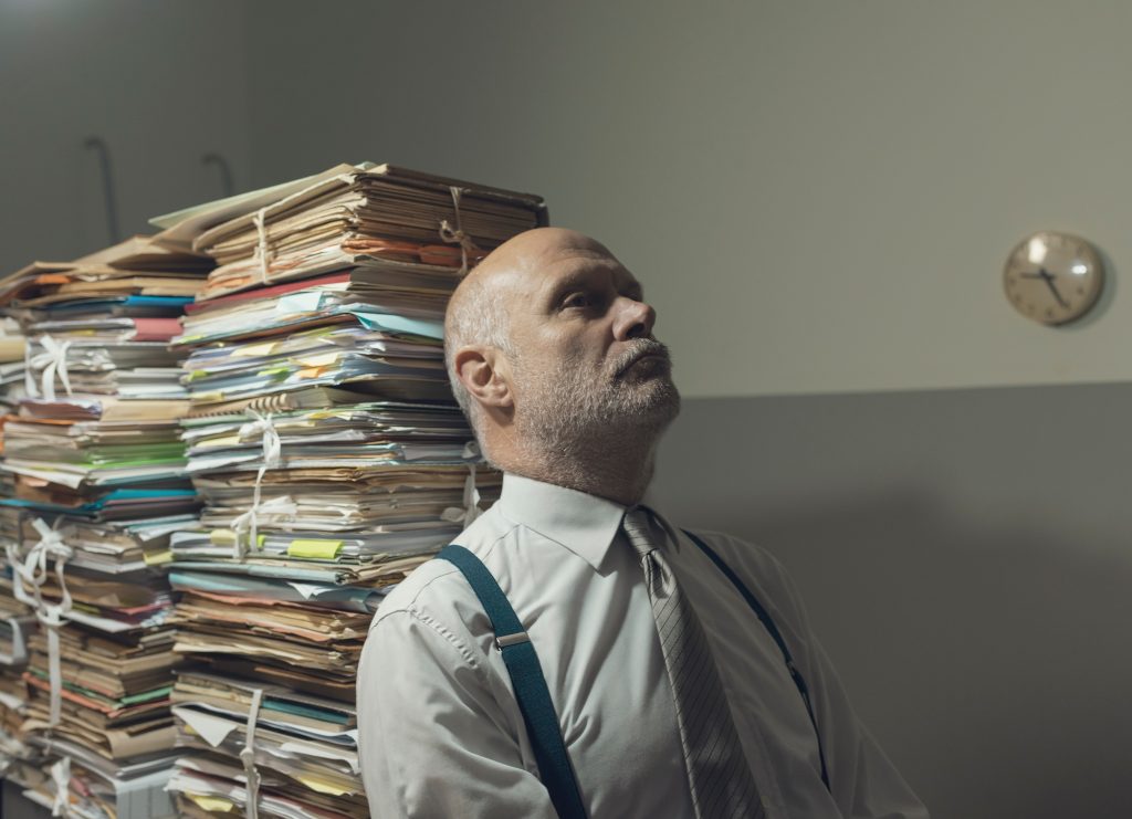 Stressed business executive overloaded with paperwork