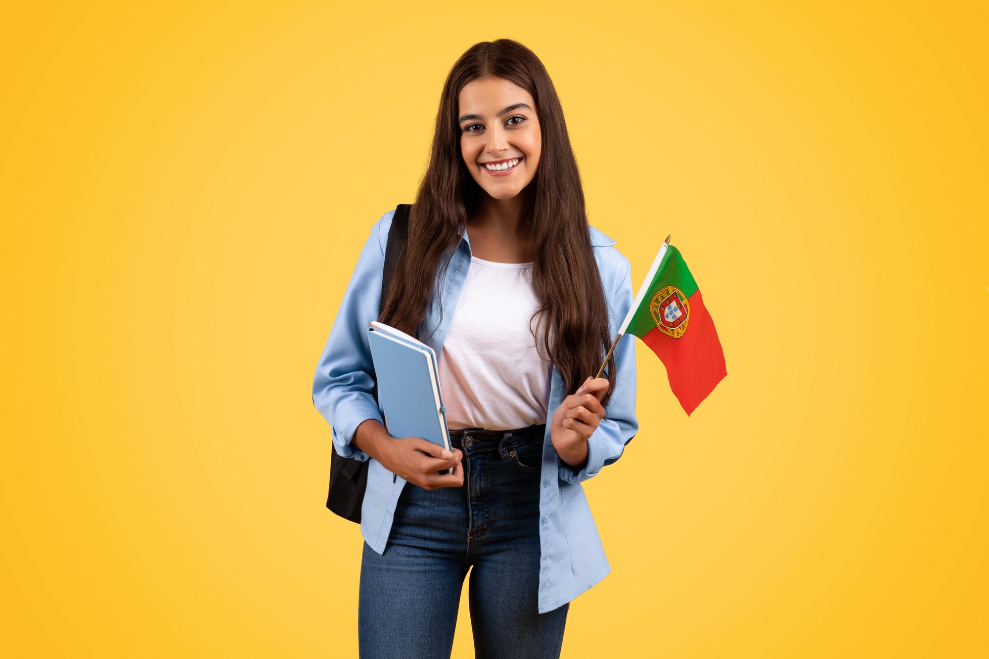 Teen student with Portugal flag, studying diligently against a bright yellow background